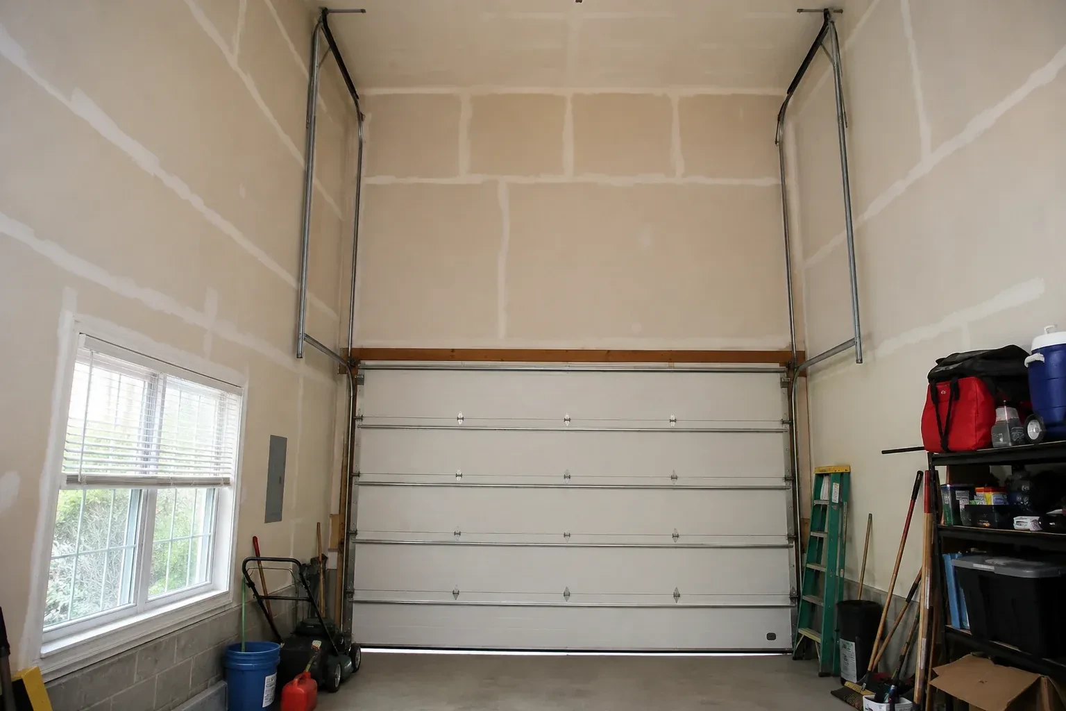 Tall garage interior with a sectional door and tracks extending into overhead space. — High-Lift Garage Door Conversion, Orangeville